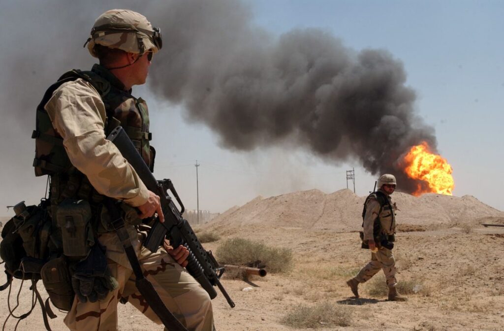 Un soldat american stă de pază lângă un puț de petrol care arde în câmpul petrolier Rumaila, Irak, aprilie 2003
