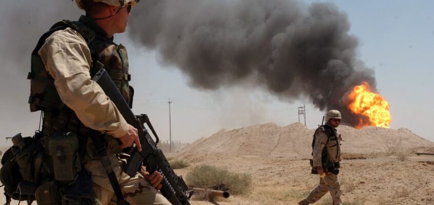 Un soldat american stă de pază lângă un puț de petrol care arde în câmpul petrolier Rumaila, Irak, aprilie 2003