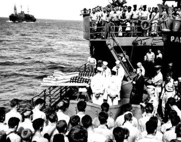 Doi soldați înrolați pe nefericitul portavion LISCOME BAY, torpilat de un submarin japonez în Insulele Gilbert, sunt îngropați pe mare de pe puntea unui transport de asalt echipat de Garda de Coastă.
