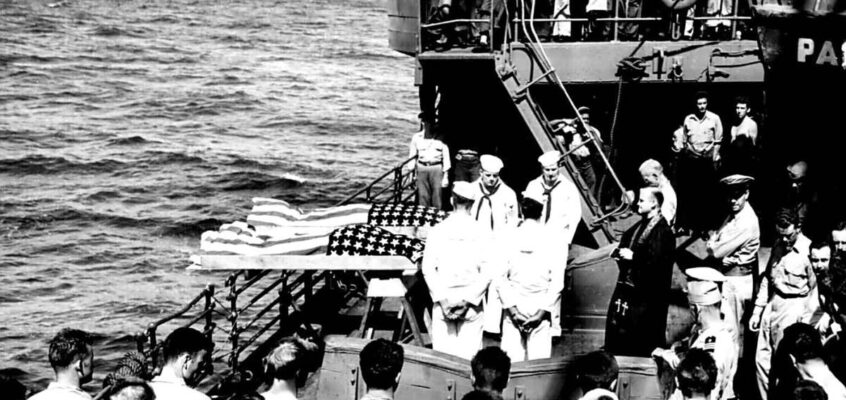 Doi soldați înrolați pe nefericitul portavion LISCOME BAY, torpilat de un submarin japonez în Insulele Gilbert, sunt îngropați pe mare de pe puntea unui transport de asalt echipat de Garda de Coastă.